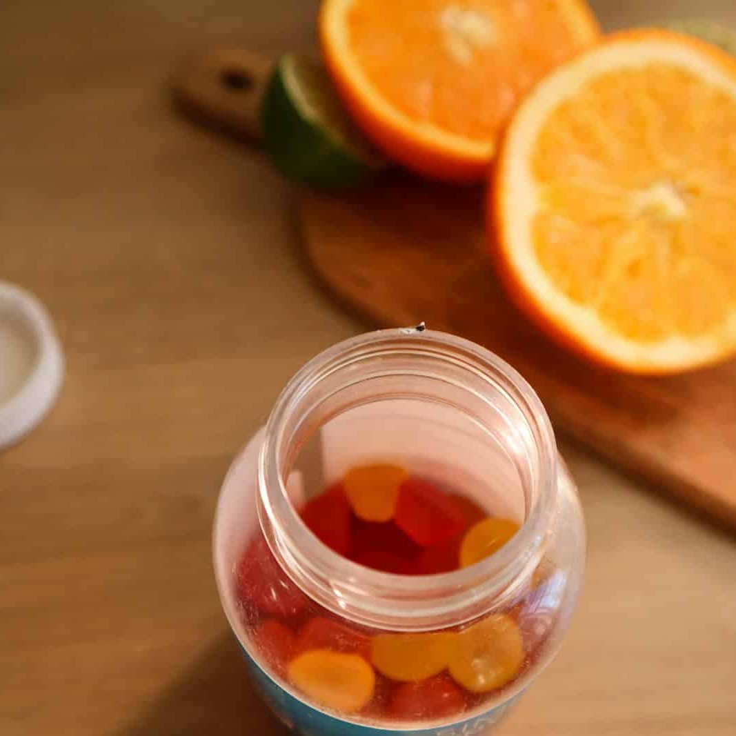 Photo by Maria Kozyr a jar filled with gummy bears next to sliced oranges